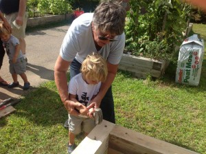 Lecturer Patty Thomas and her grandson help build a raised bed at the Kennedy School in Canton.